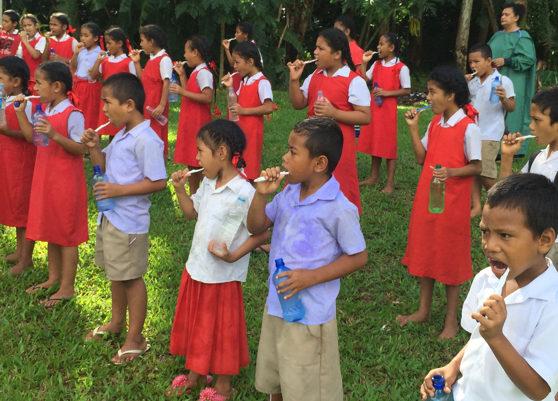 Children brush their teeth outside school in Tonga